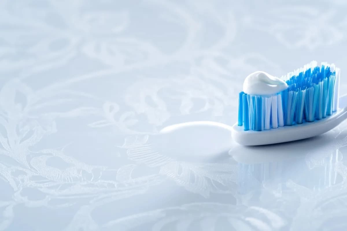 Eine weiche Zahnbürste mit etwas weißer Zahnpasta liegt auf einer sauberen PVC-Tischdecke